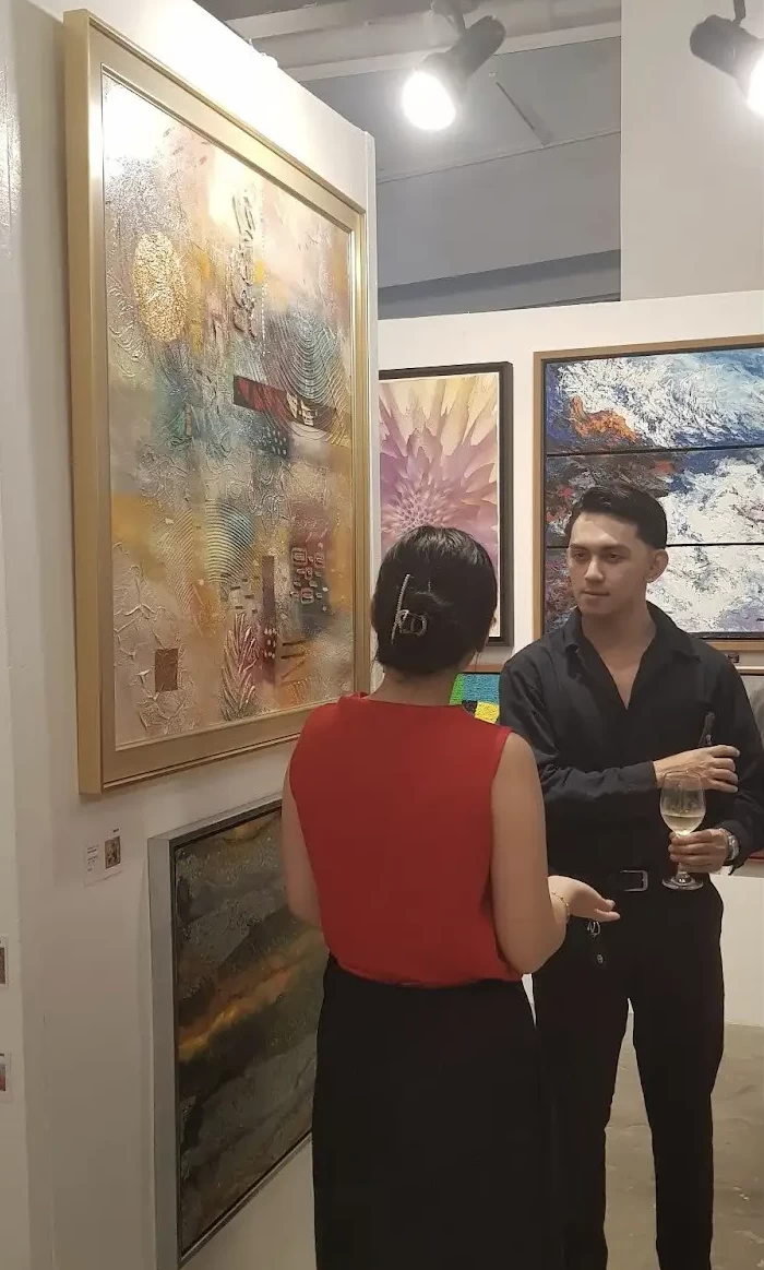 Artist Jericho Pierre Curañes having a discussion with a guest at the opening of “Brainstorm 3”